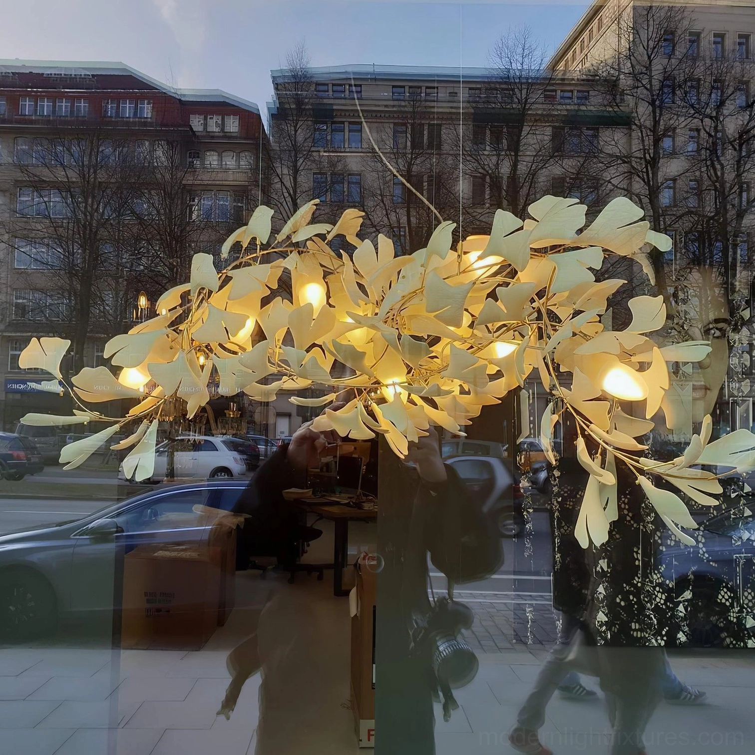 Ginkgo leaf chandelier eye-level street view showcasing warm gold finish and lifelike botanical leaf decorative lighting in outdoor urban setting