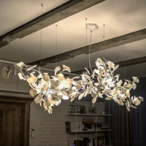 Ginkgo leaf chandelier installed in indoor home interior with warm ambient lighting, exposed wooden ceiling beams, mixed gold and cream leaf accents