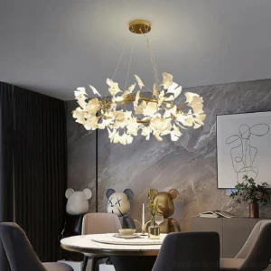 Modern ginkgo leaf pendant chandelier with warm glowing ceramic leaves and gold hardware in contemporary dining room setting