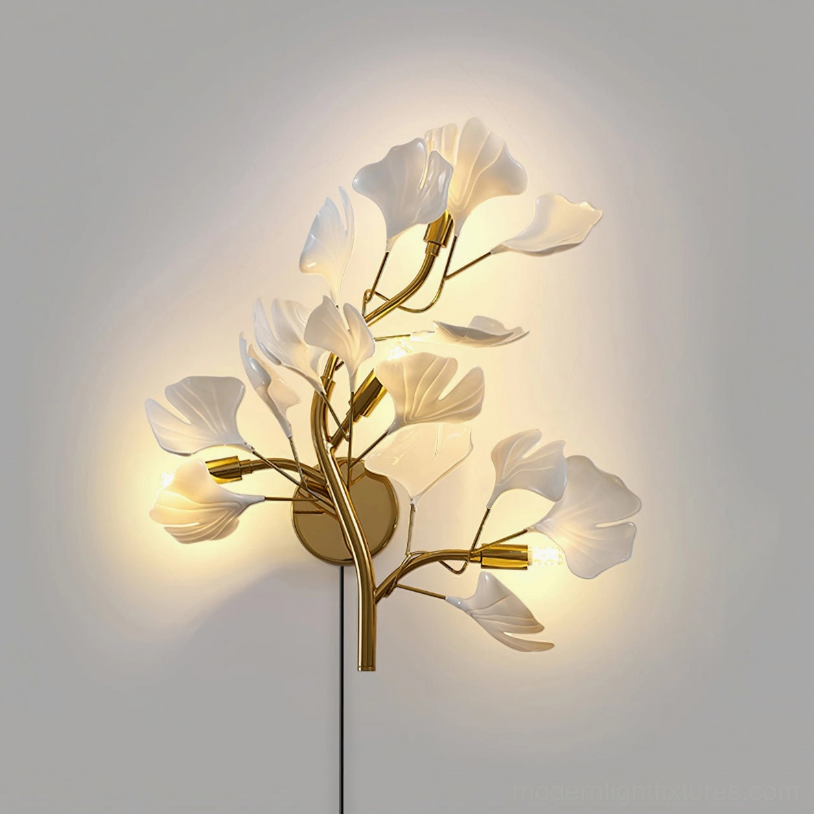 Modern ginkgo leaf wall sconce demonstrating warm ambient light cast on surrounding wall surface