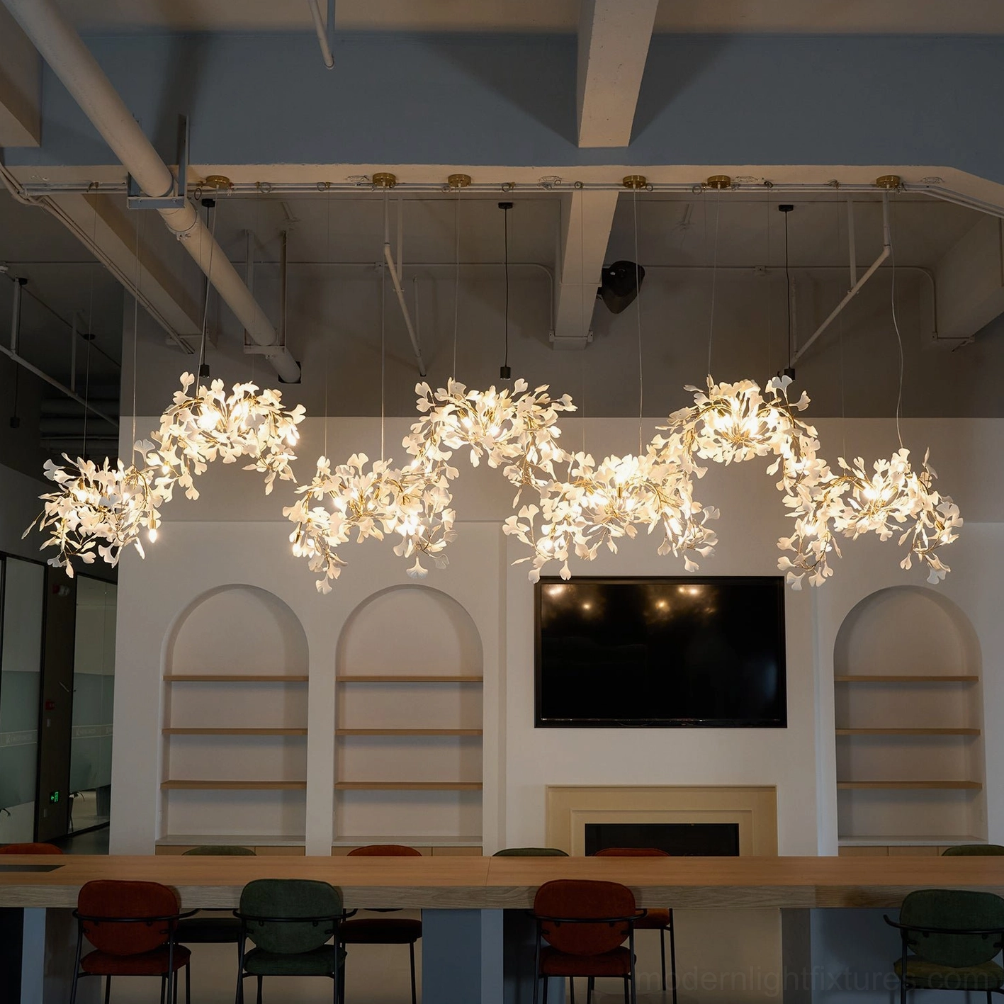 Modern ginkgo leaf pendant chandelier with warm glowing illumination in contemporary office meeting room setting