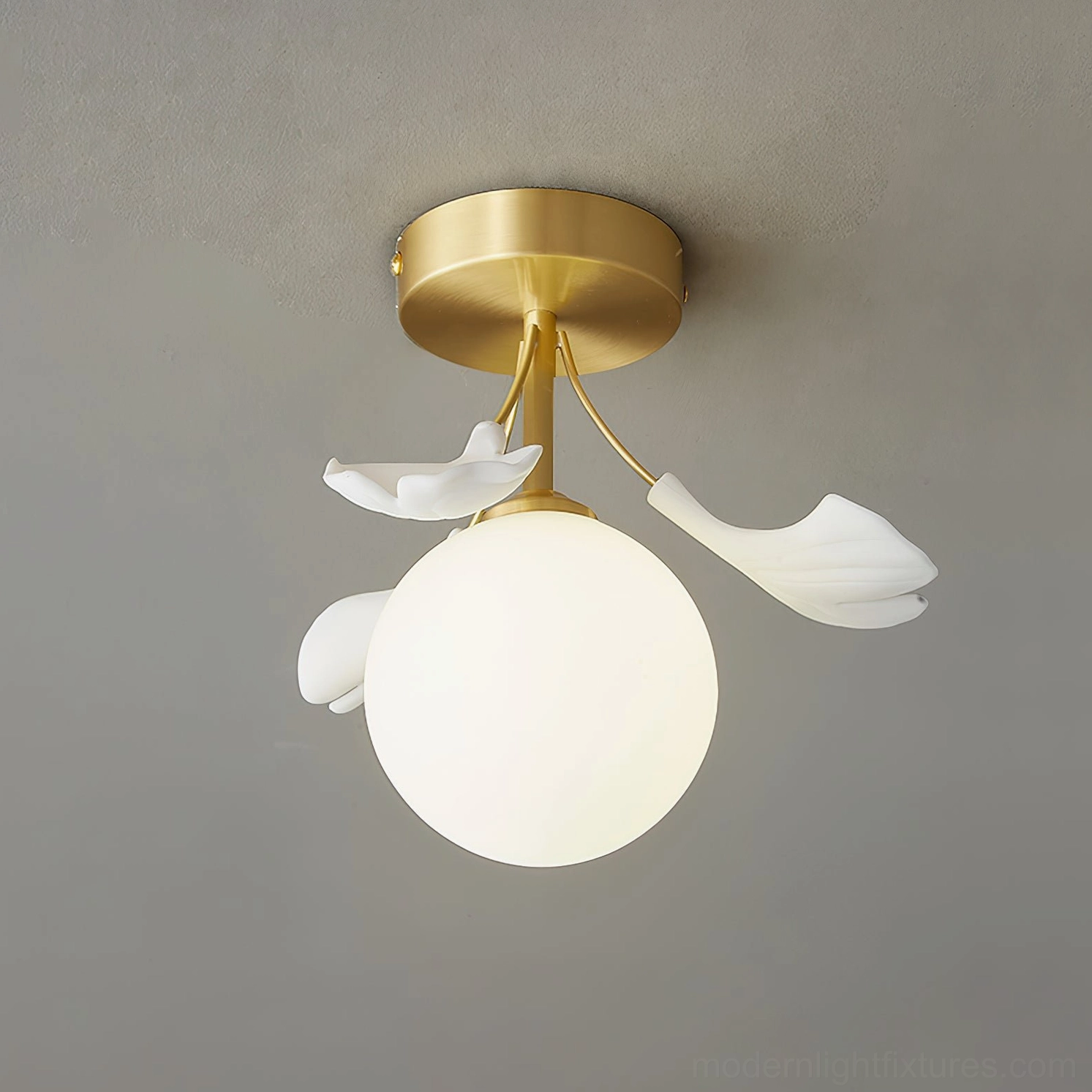 Ginkgo Rosalia brass and white ceiling light with lit frosted glass globe against grey ceiling