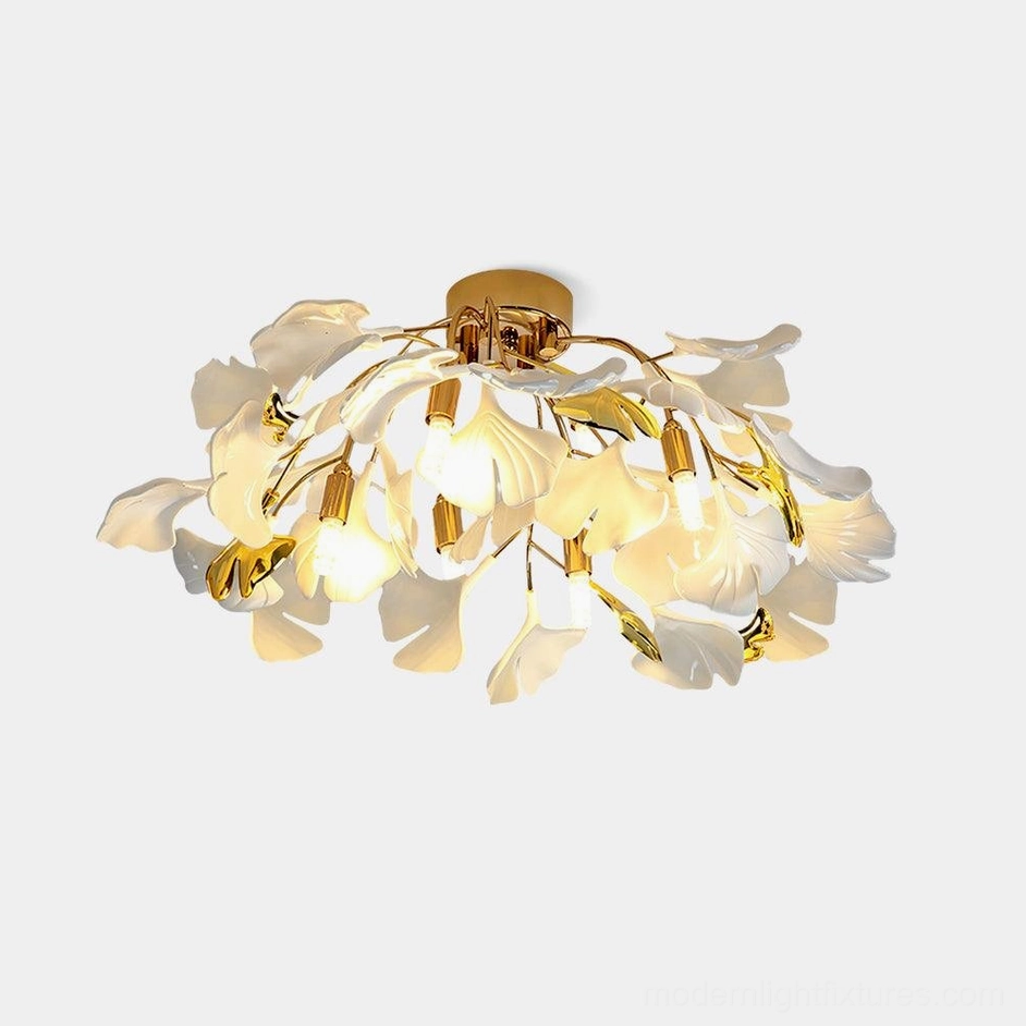 Ginkgo Valla modern ceiling light with gold metal frame and white ceramic ginkgo leaf design on plain white studio background, front view close-up