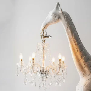 Side close-up detail of giraffe floor lamp showing spotted resin texture and glowing crystal candle chandelier pendant