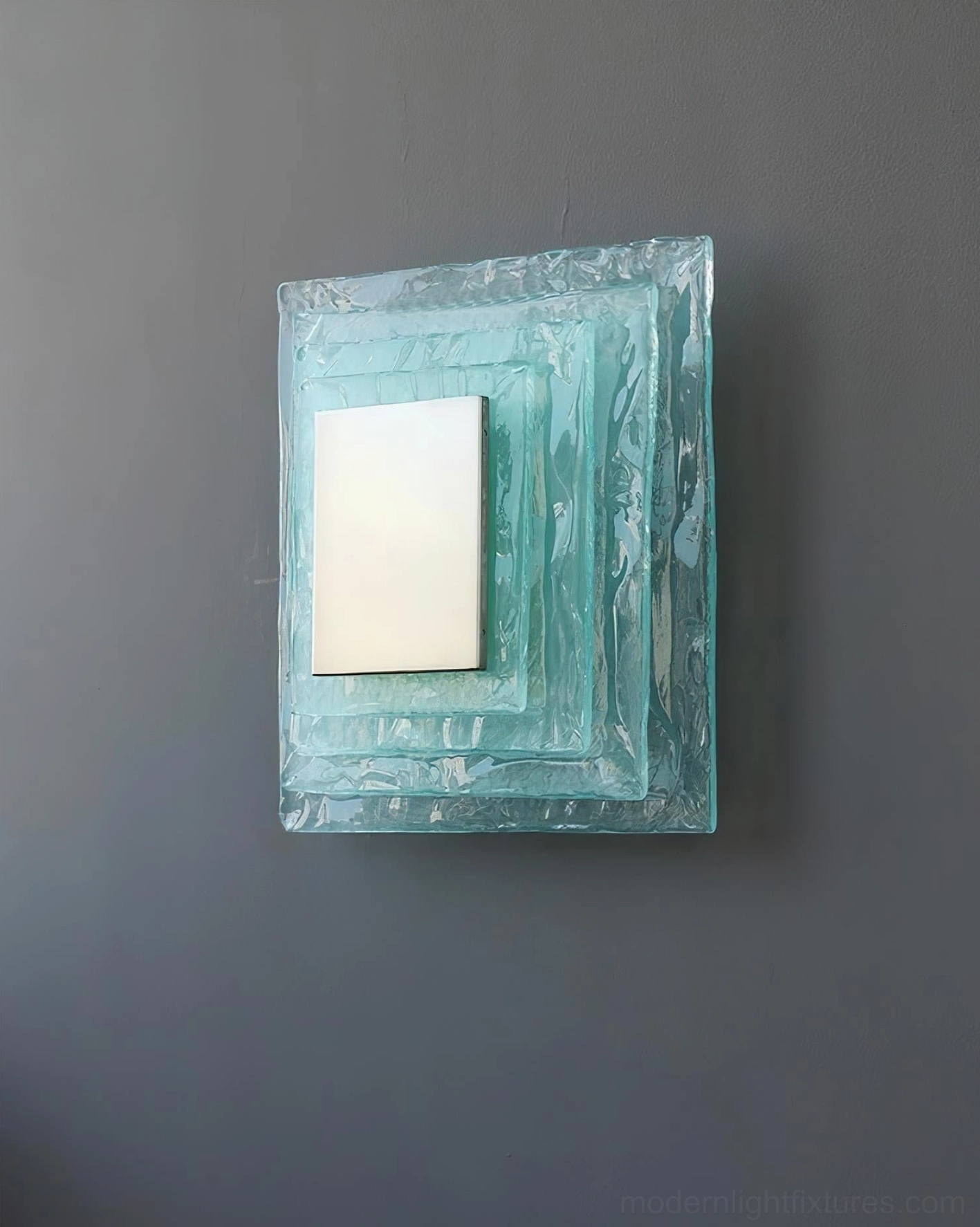 Glacira modern wall sconce mounted on dark gray wall, contemporary frosted glass fixture with geometric layers