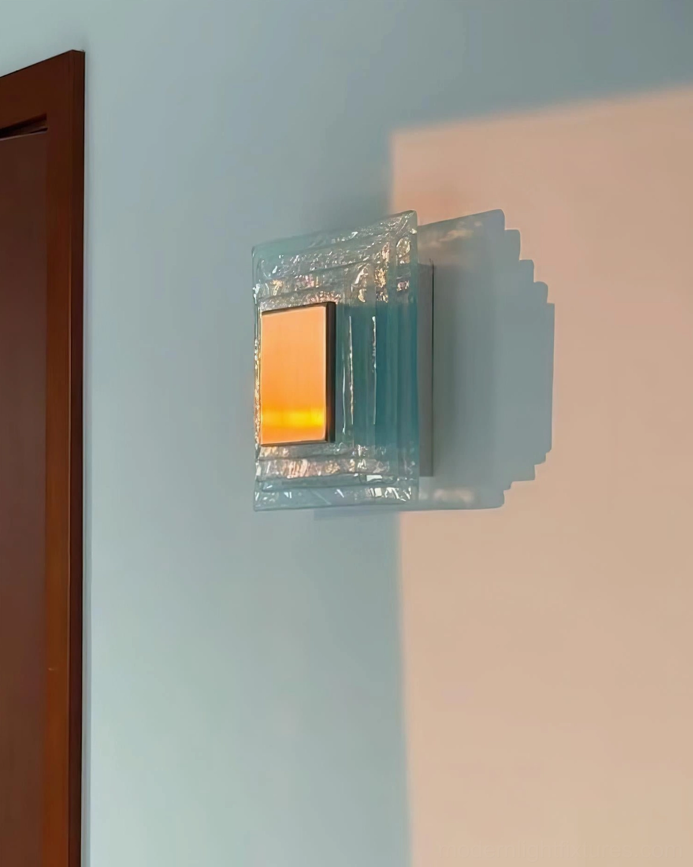 Glacira wall sconce front mounted view showing geometric layered glass construction and metal backing panel
