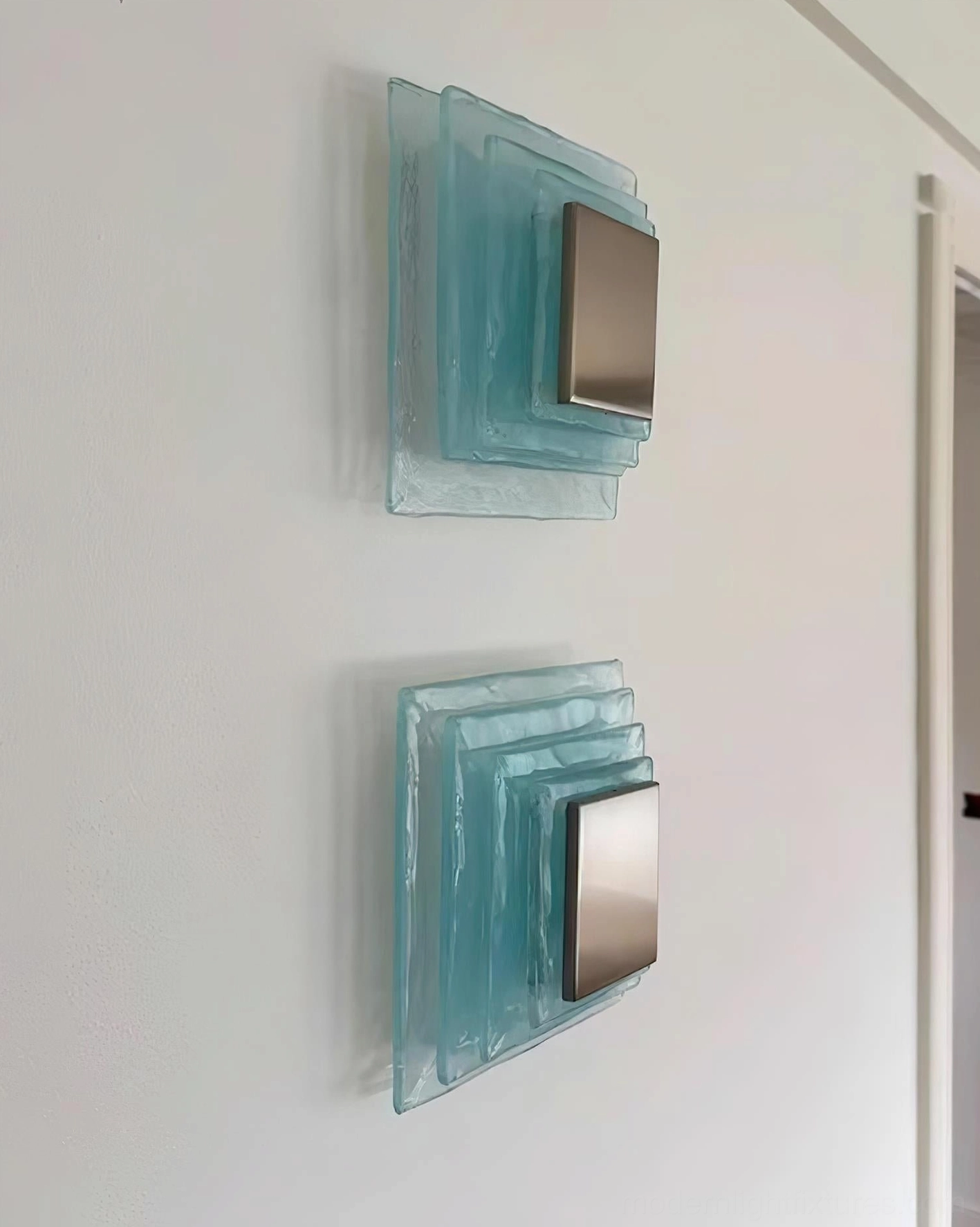Glacira frosted glass wall sconces installed pair on white residential corridor wall, modern Scandinavian style lighting