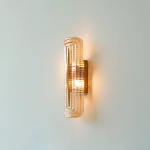 Illuminated Glacium wall sconce casting warm crystalline light on light gray interior wall