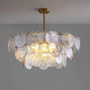 Glass disc pendant chandelier close-up low angle showing illuminated multi-layer disc shades and brass suspension