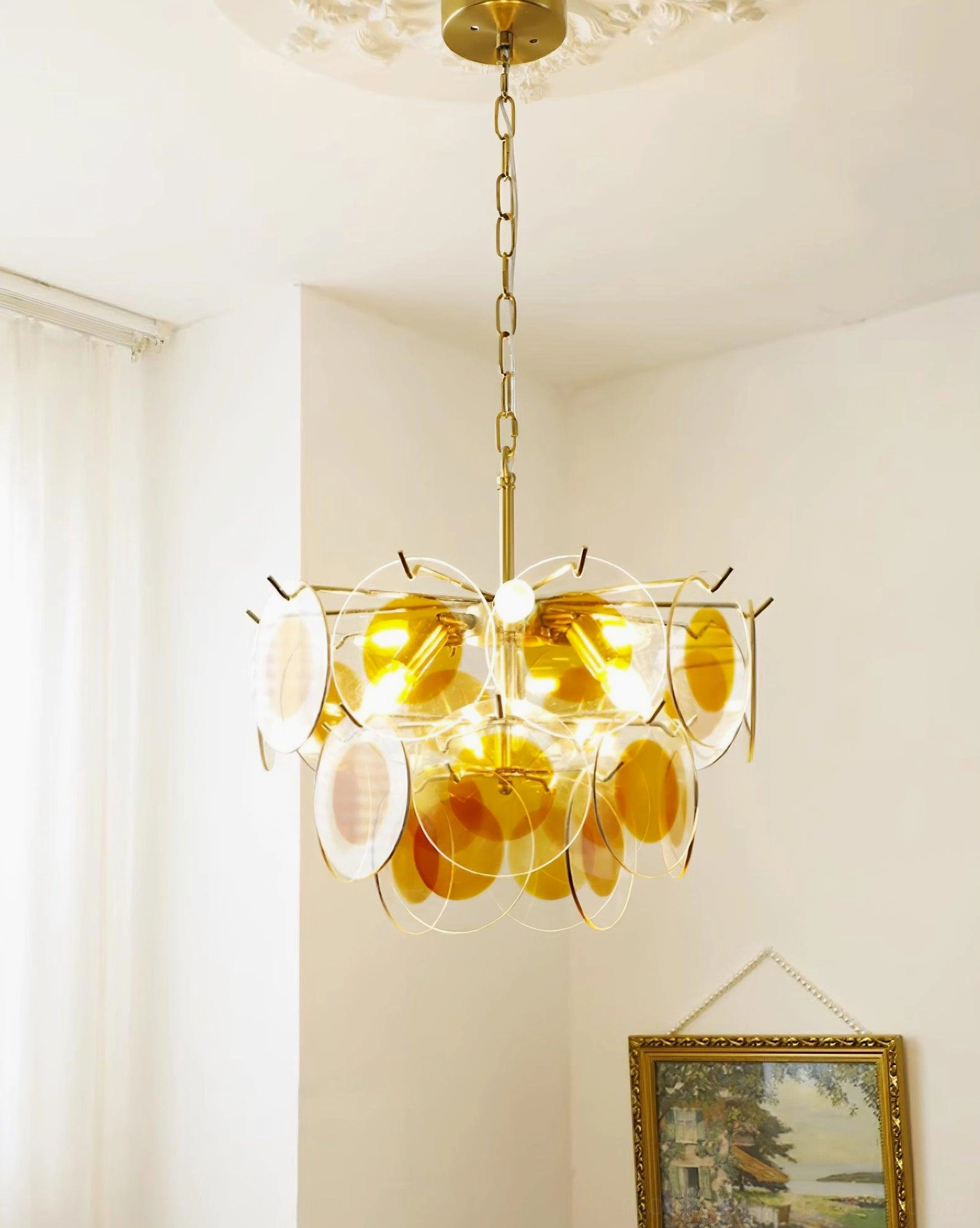 Modern glass disc chandelier polished brass finish minimalist dining area white wall high angle view