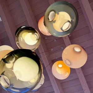 Multi-head glass globe chandelier suspended in residential attic space with warm interior lighting, showing luxury modern installation