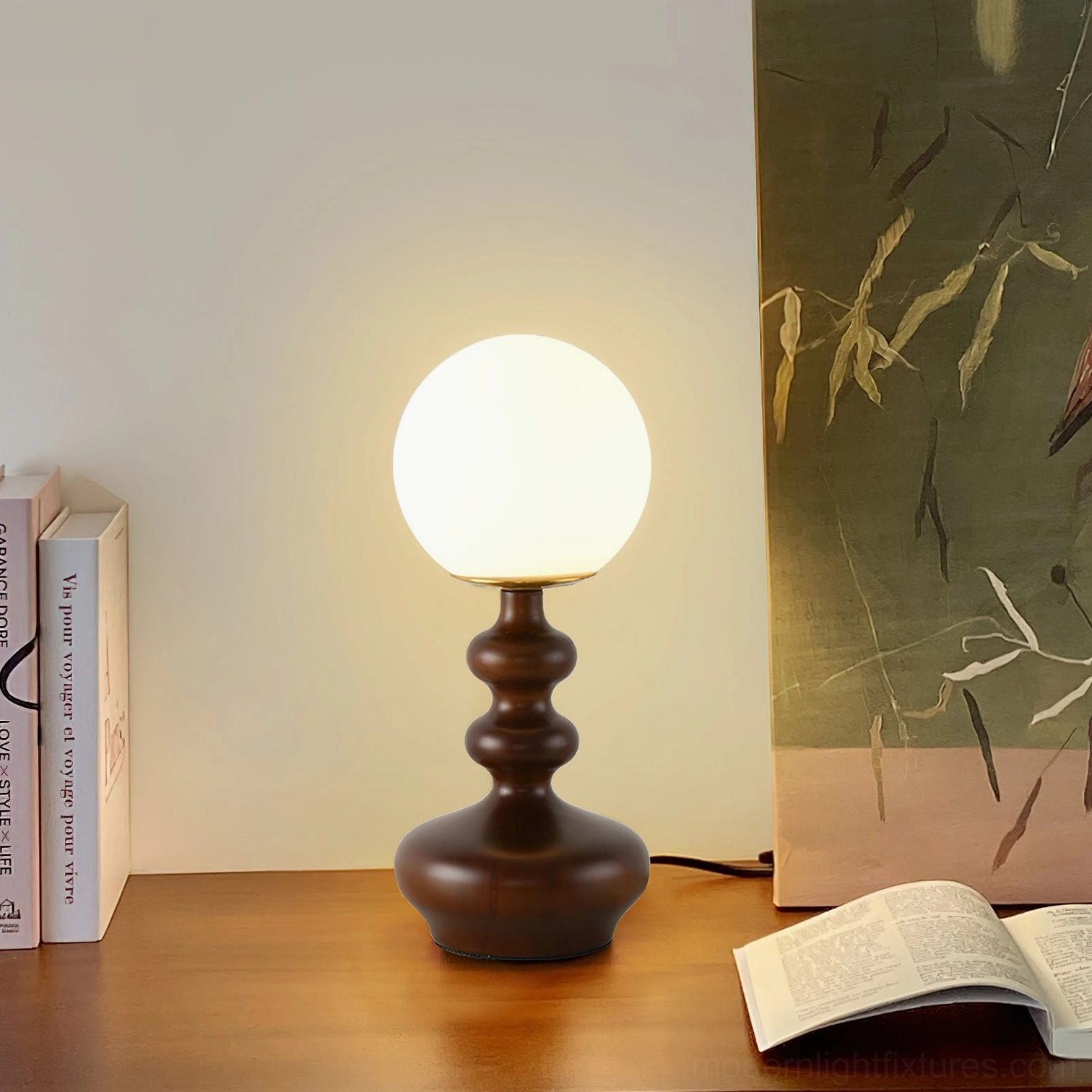 Gleason modern globe lamp with dark turned wood stem positioned on wooden desk with books and home decor