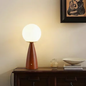 Gleason frosted glass table lamp illuminated on bedroom dresser with warm reddish-brown tapered wood base