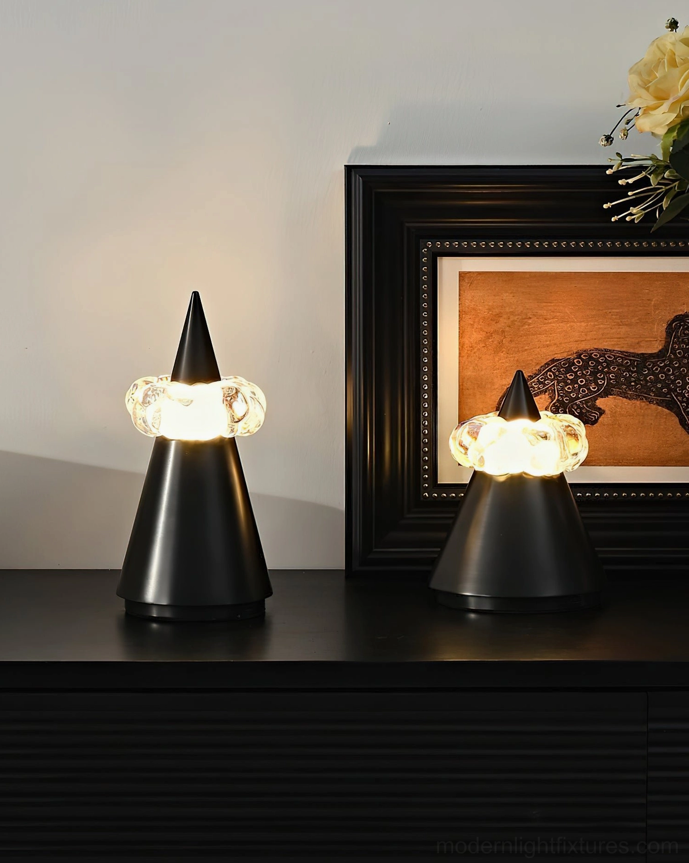 Matte black brushed metal table lamp paired on dark wood console with framed wall art and decorative accessories, modern luxury home styling