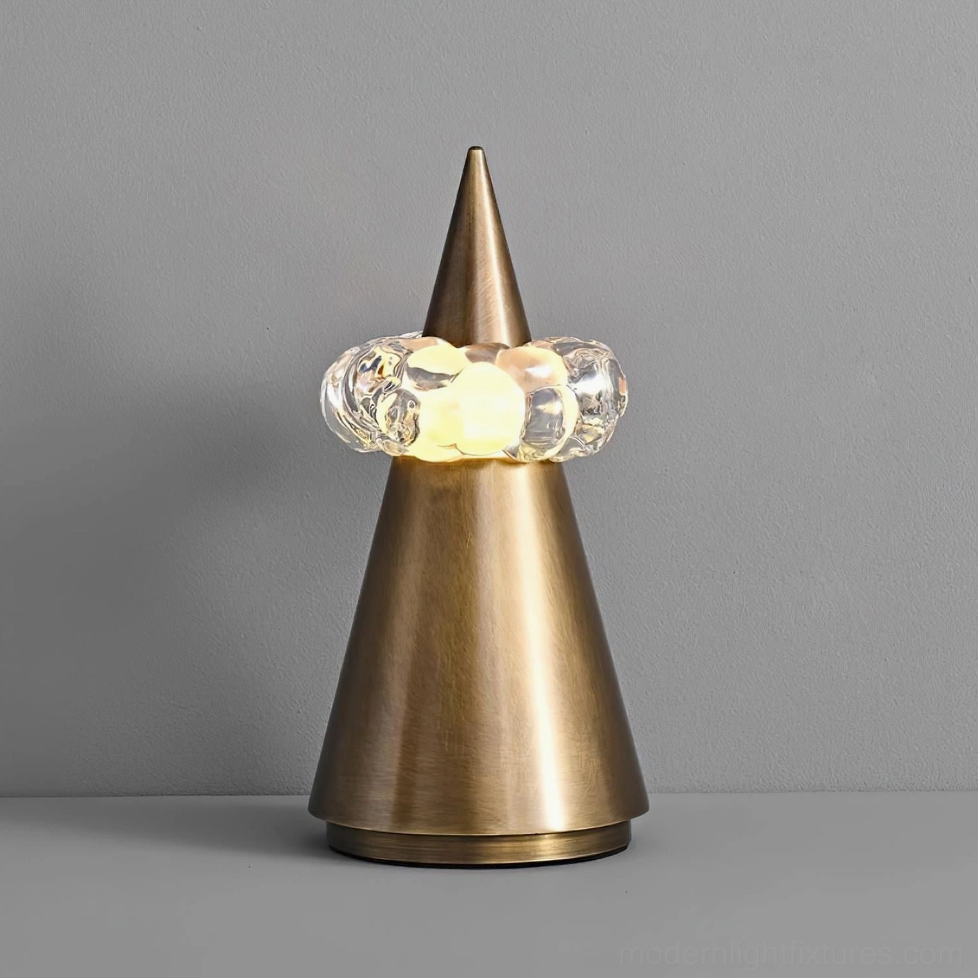 Modern minimalist table lamp with tapered conical silhouette and crystal orb diffuser, warm ambient lighting on gray backdrop