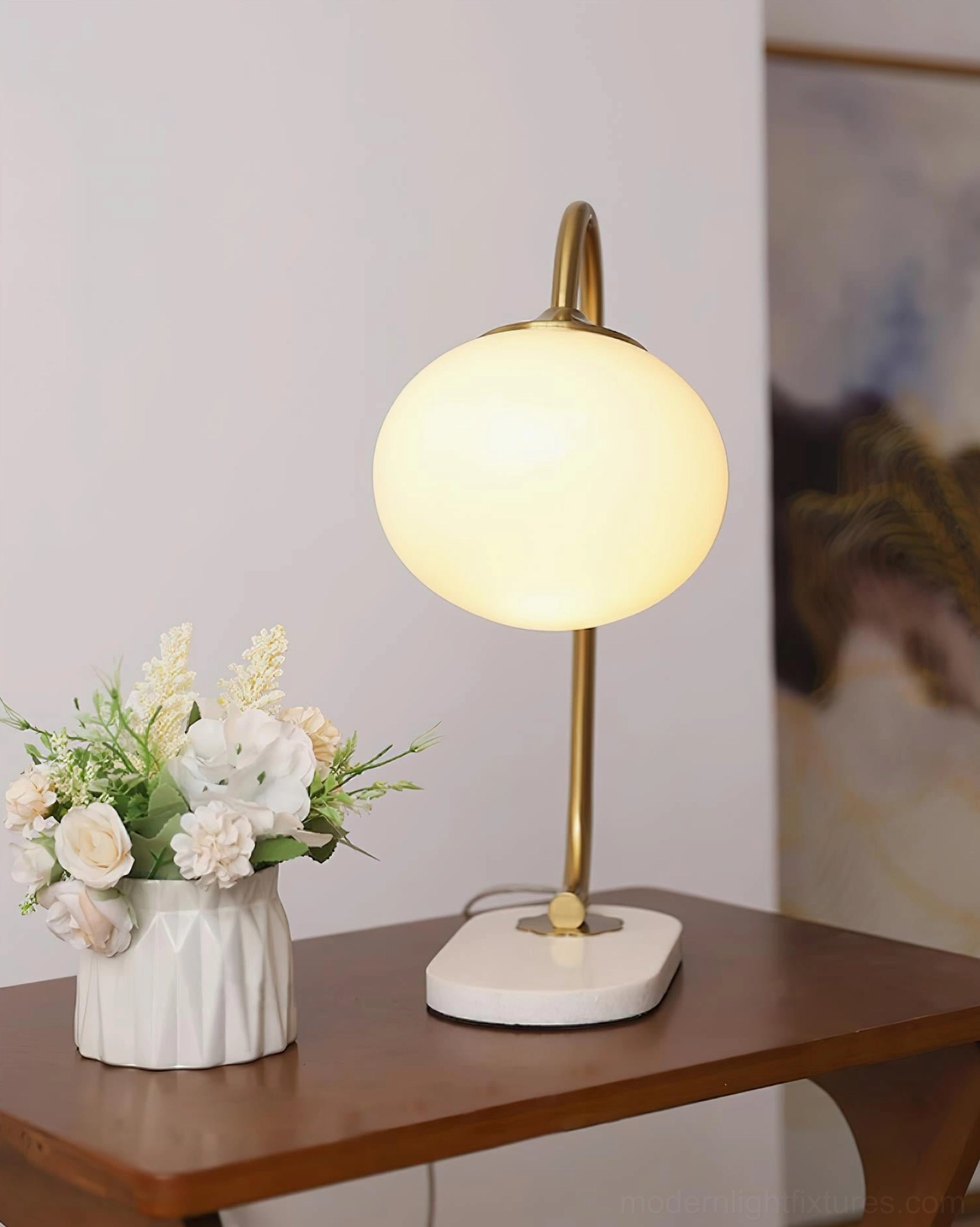 Globe table lamp with gold curved metal frame and pink glass shade detail view