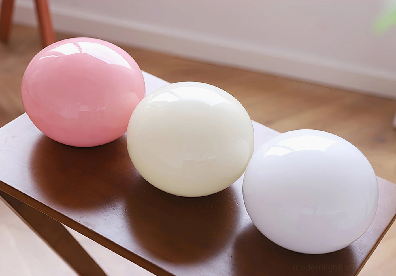 Three spherical glass lamp shades in pink, off-white, and frosted clear displaying color options