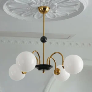 5-light globe pendant chandelier installed on ornate ceiling showing polished brass hardware and warm cognac glow