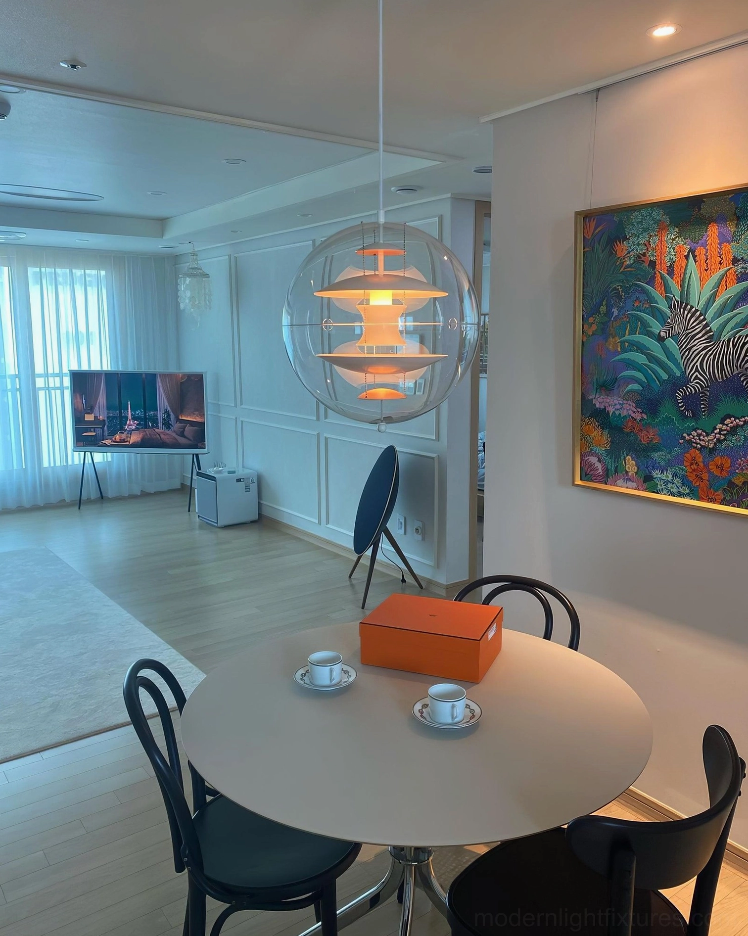 Globe pendant light with visible multi-layered aluminum interior and clear acrylic shade in minimalist setting