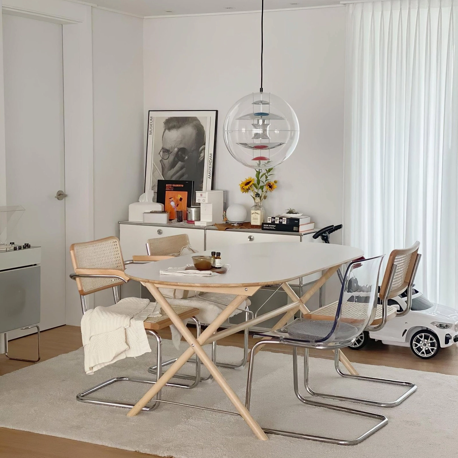 Globe pendant light suspended in dining area with contemporary dining furniture and minimalist wall decor
