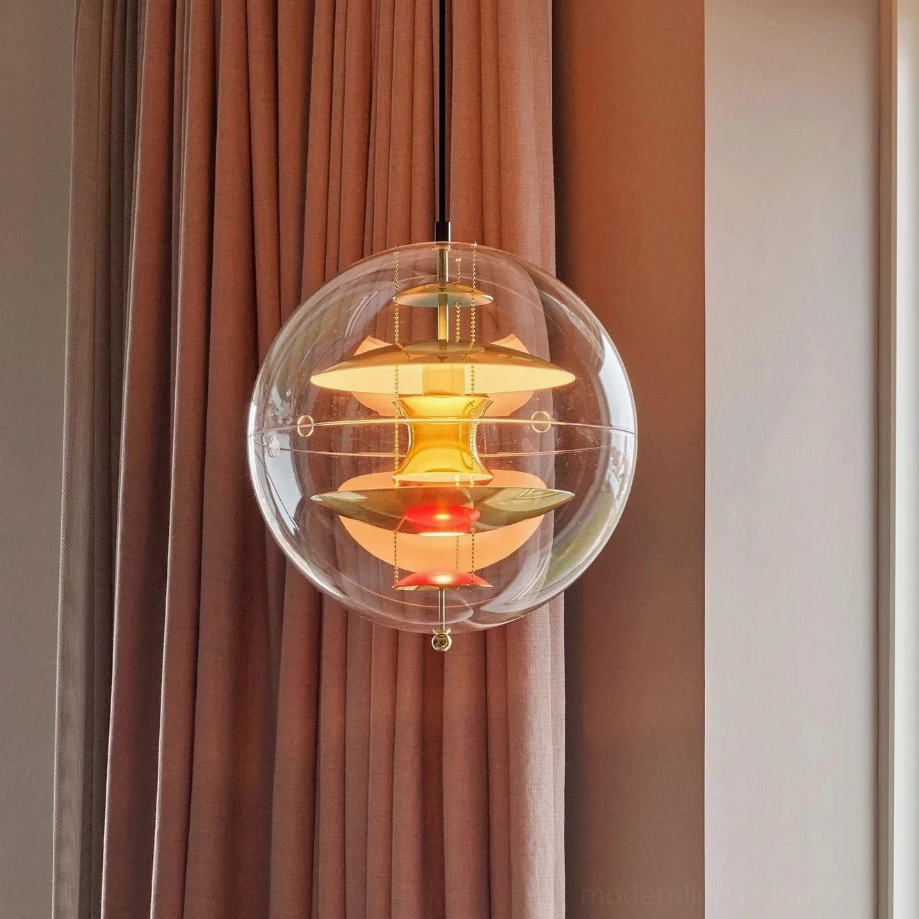 Globe pendant light illuminated showing warm glow through clear acrylic shade with multi-layered aluminum interior structure