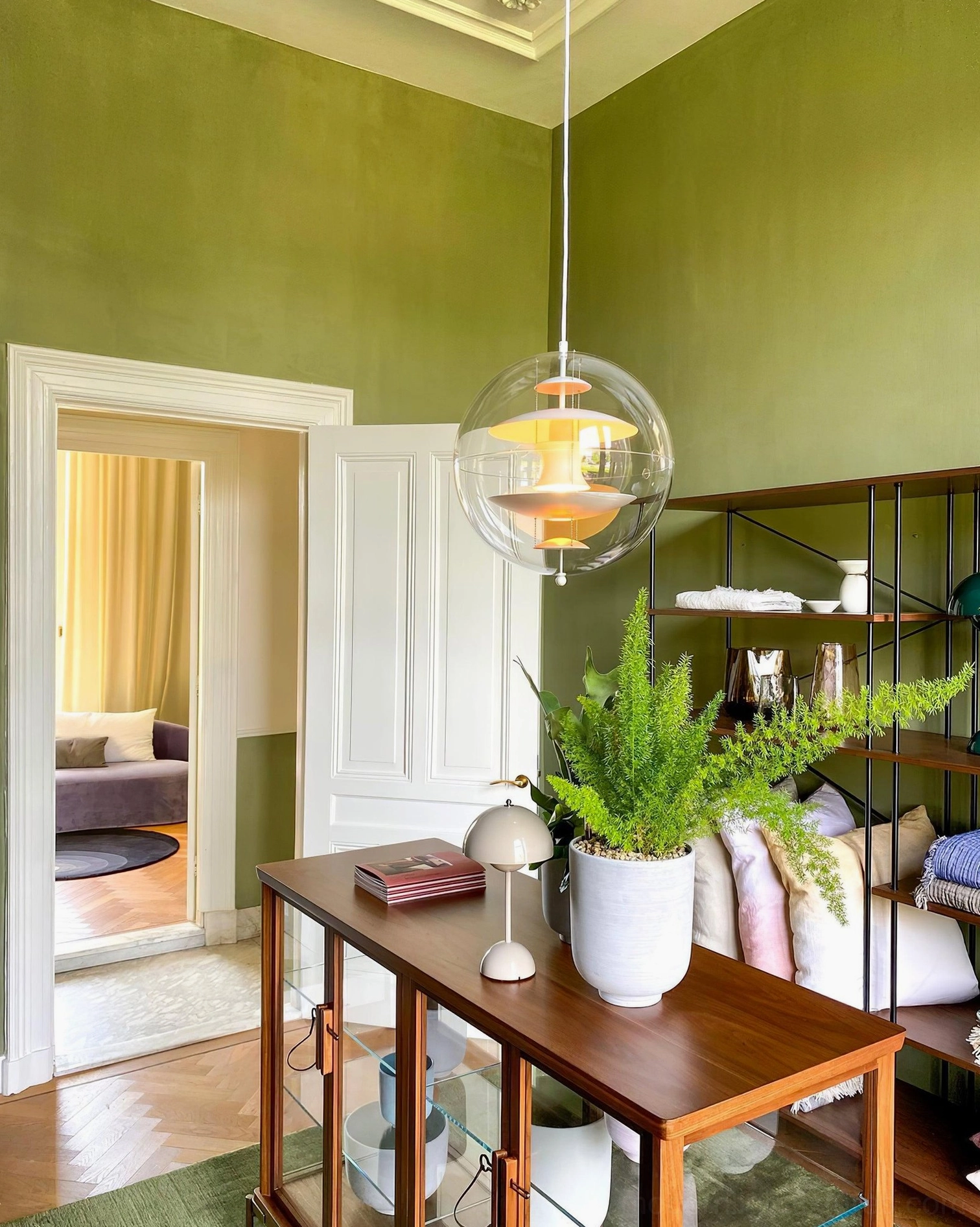 Pendant light fixture with spherical transparent design and metal hardware in modern interior space