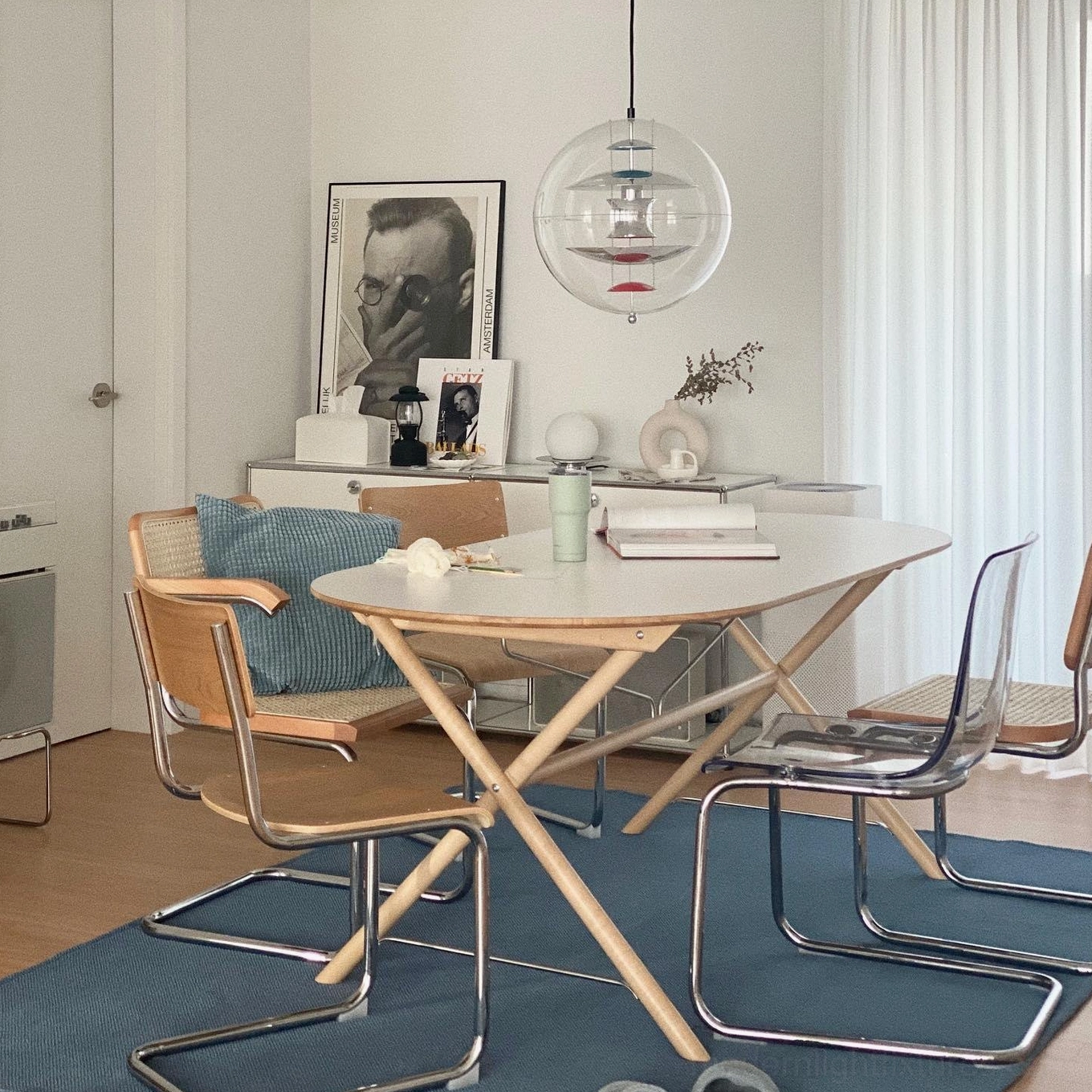 Modern globe pendant light illuminating Nordic-style dining space with light wood table and contemporary chairs