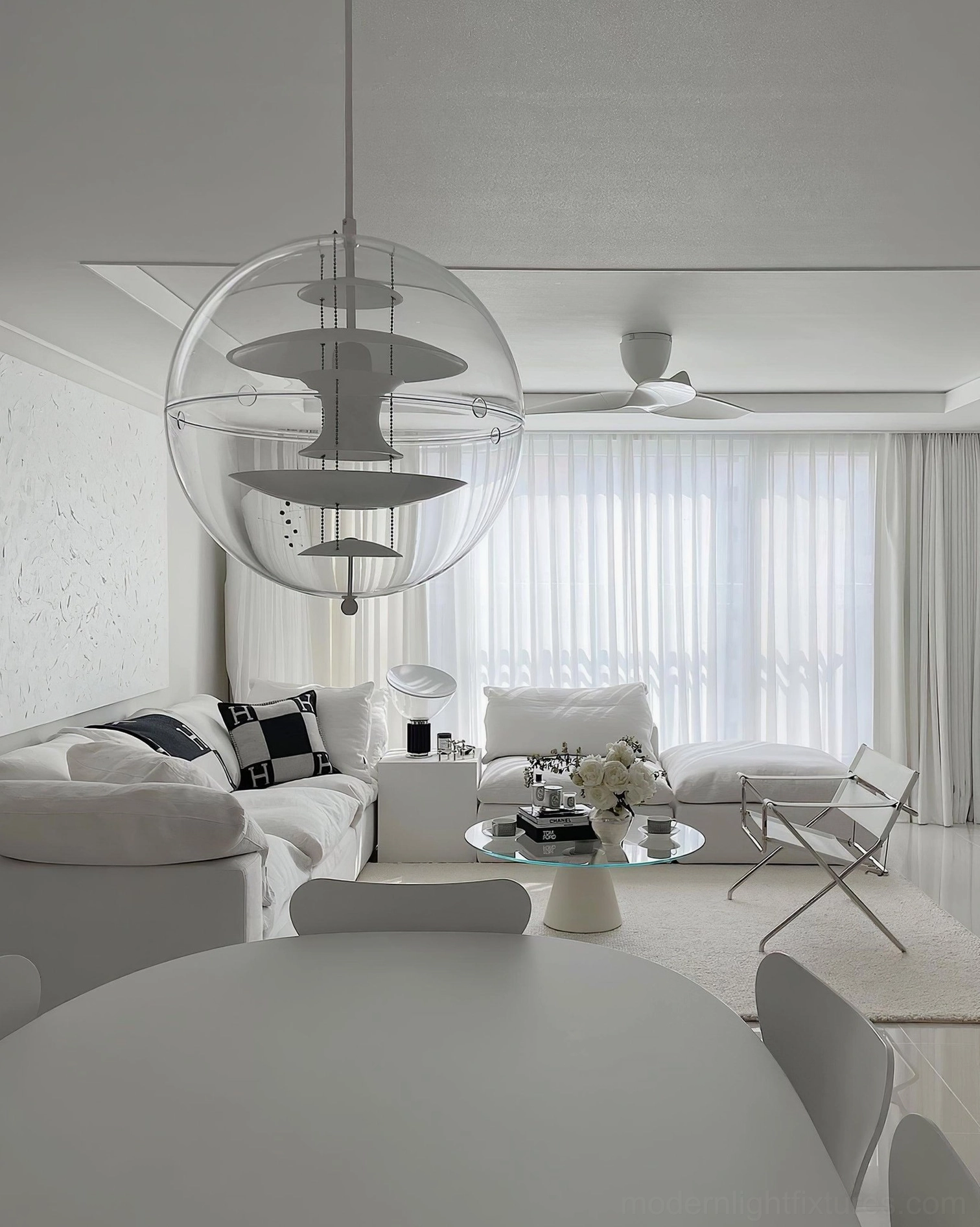 Transparent acrylic sphere pendant light with visible metallic interior layers in bright modern room