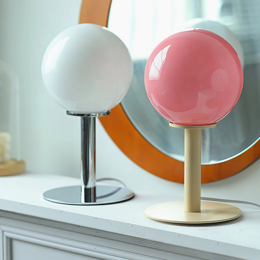 Two globe table lamps with beige and chrome metal bases and pink white shades on vanity table with mirror