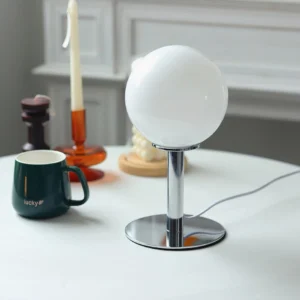 Minimalist globe table lamp with chrome polished base and white spherical shade in dining room setting
