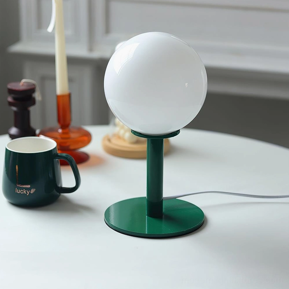 Contemporary globe table lamp with dark green metal stand and white glass shade on dining table
