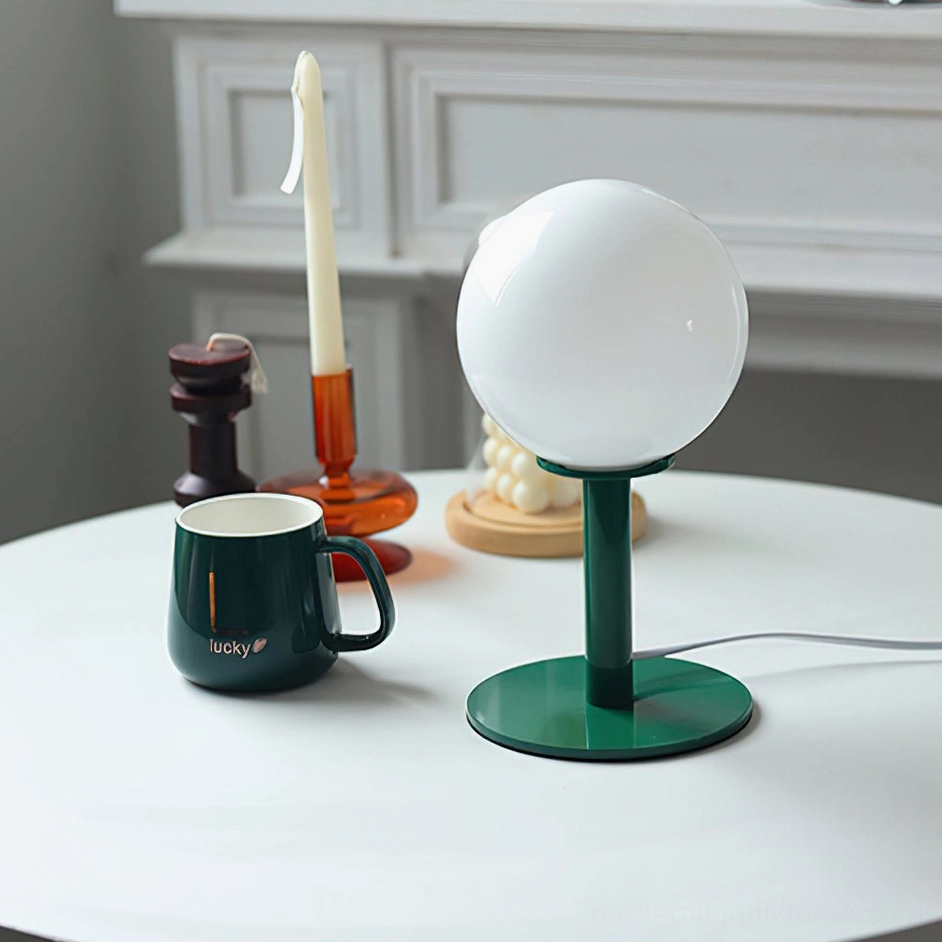 Sleek globe table lamp featuring dark green metal stand and white spherical glass shade interior scene