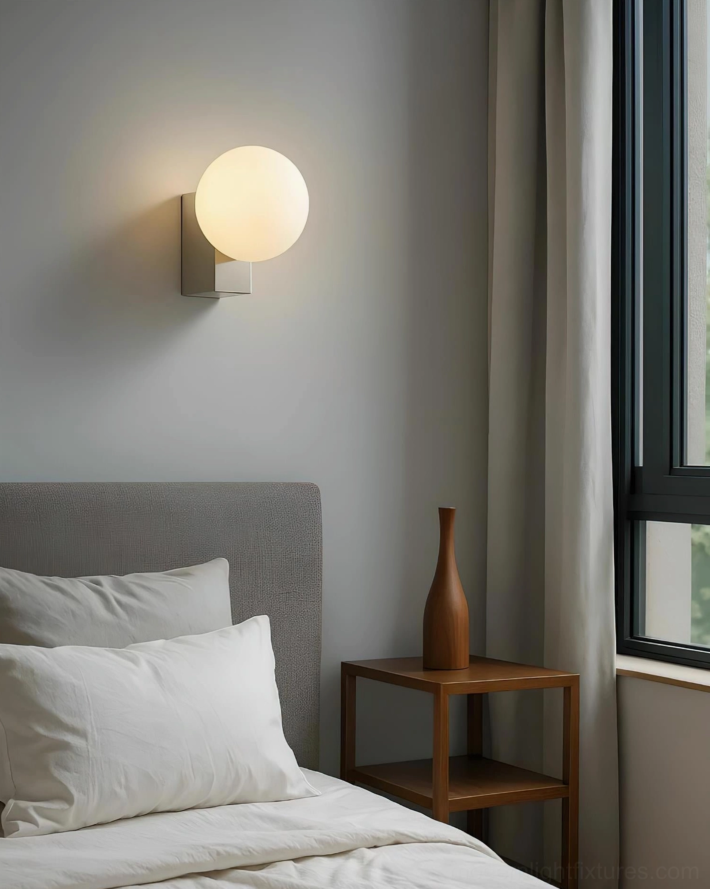 Chrome metal base Glowen wall sconce with frosted glass globe near bedroom window, modern minimalist installation