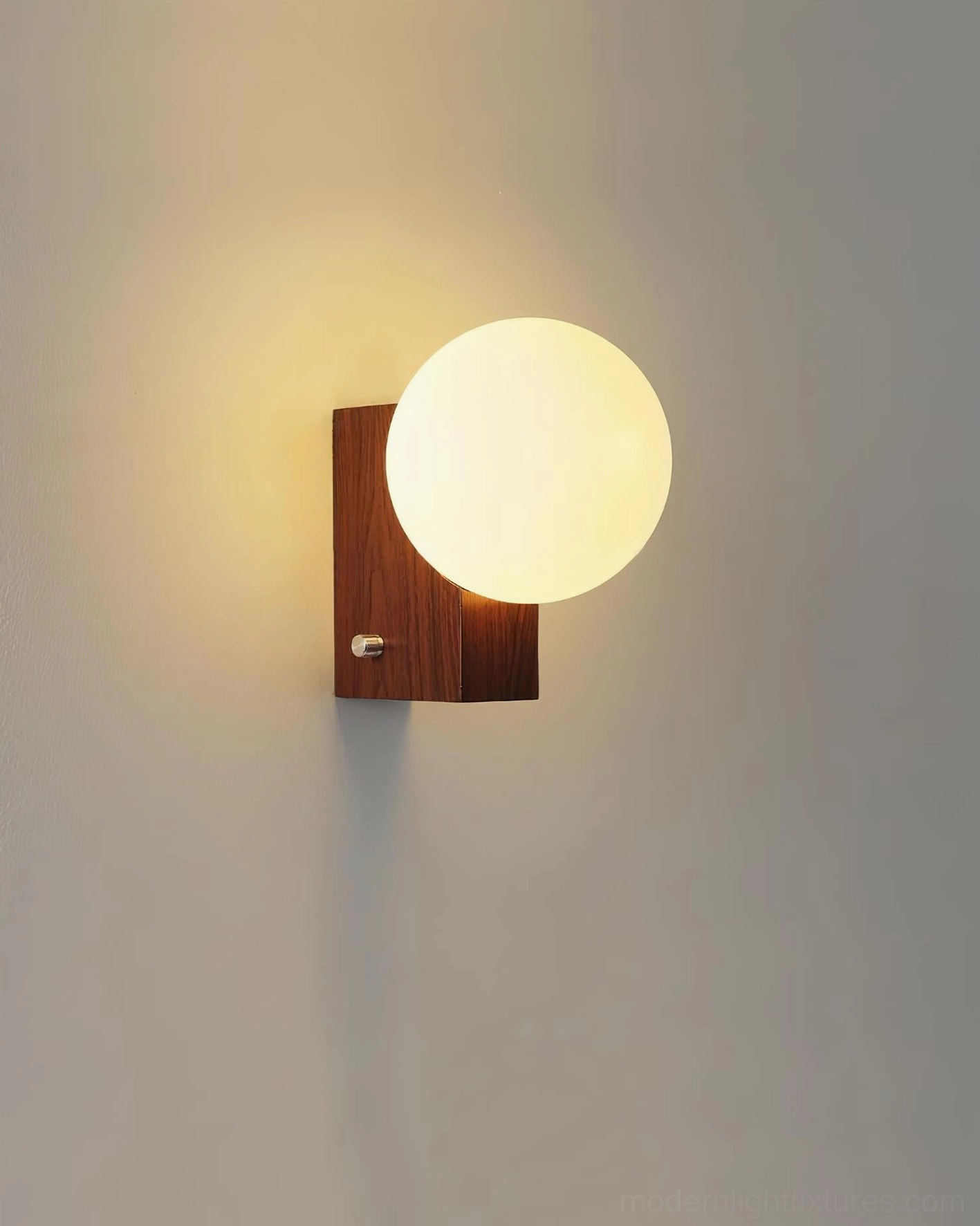 Glowen wall sconce close-up with walnut base and illuminated frosted glass globe, minimalist metal switch detail