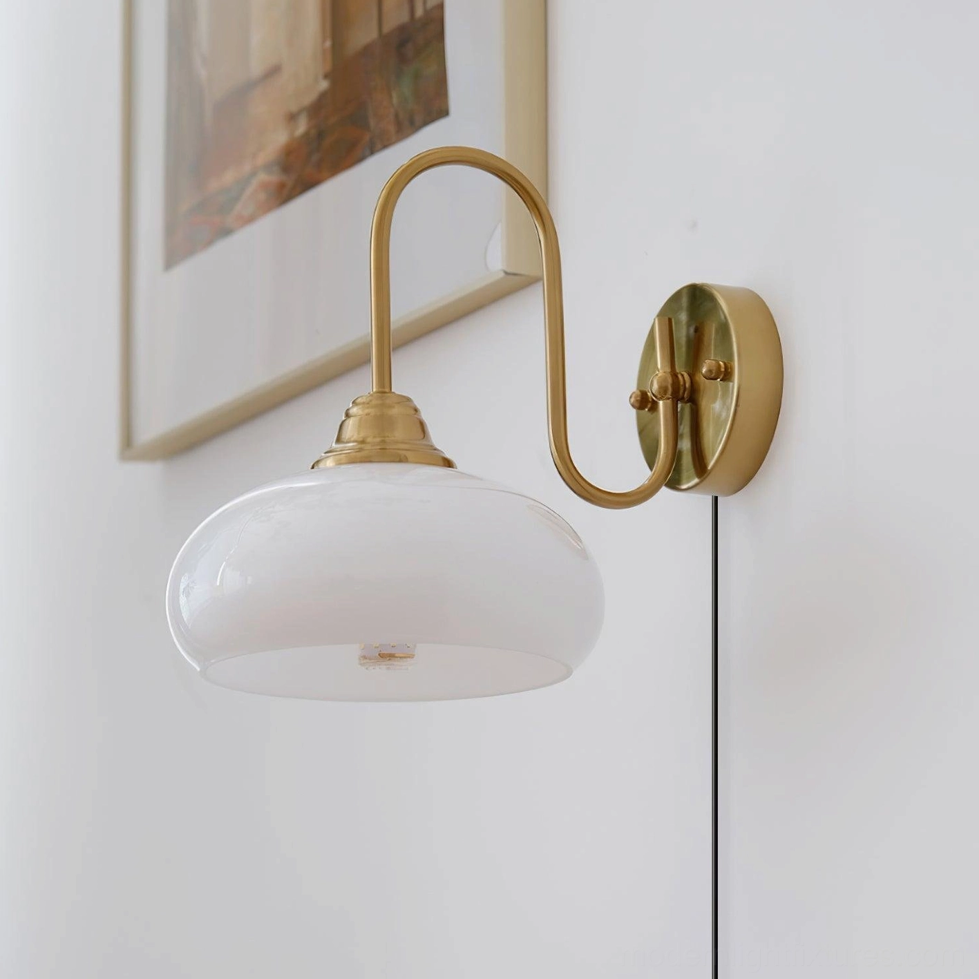 Gold brass plug-in wall sconce with textured glass shade paired on modern gallery wall with framed prints and minimalist décor