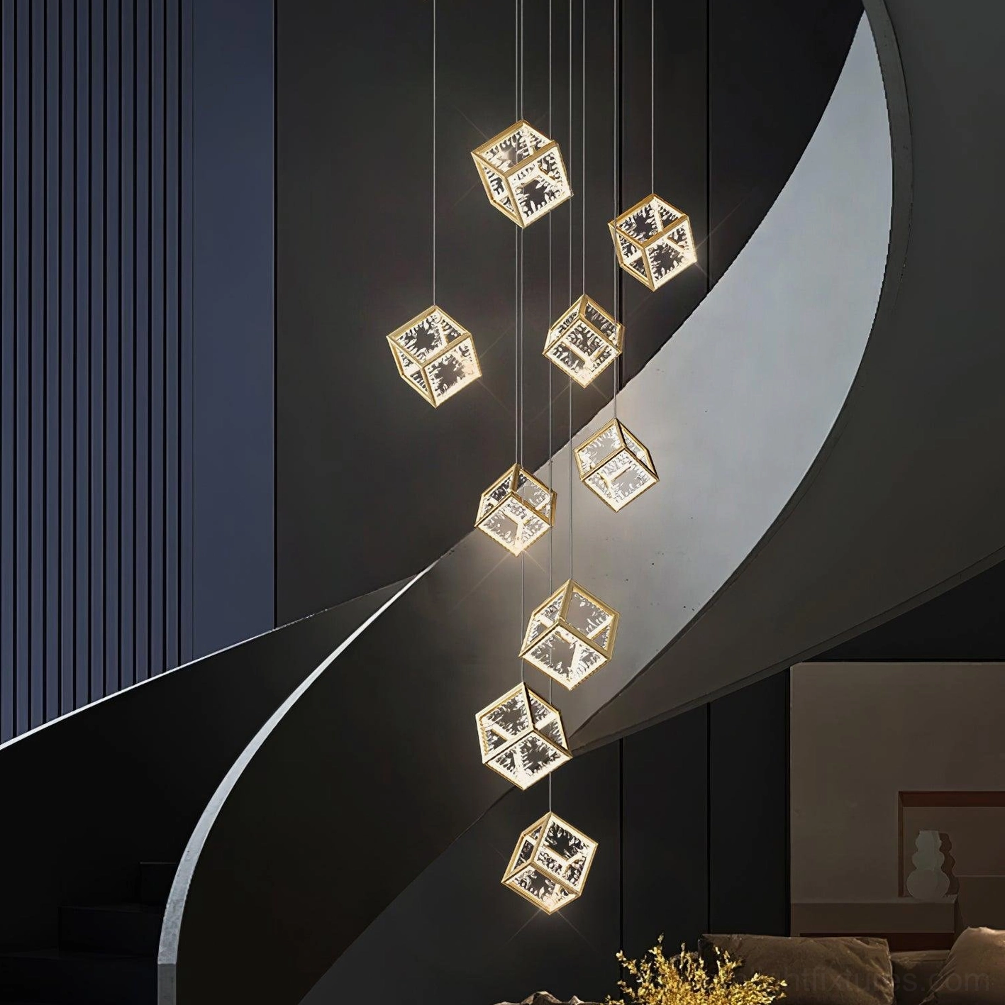 Modern gold cubic pendant chandelier installed in spiral stairwell with warm ambient lighting