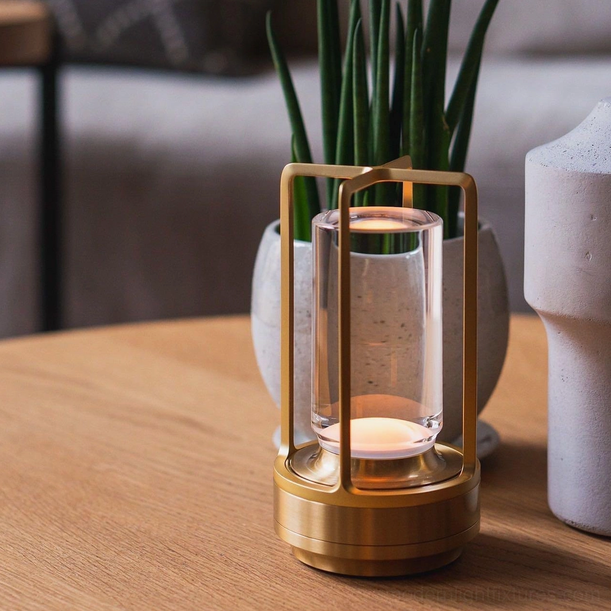 Gold cordless table lamp on home dining table with green potted plants and ceramic vases, warm ambient lighting
