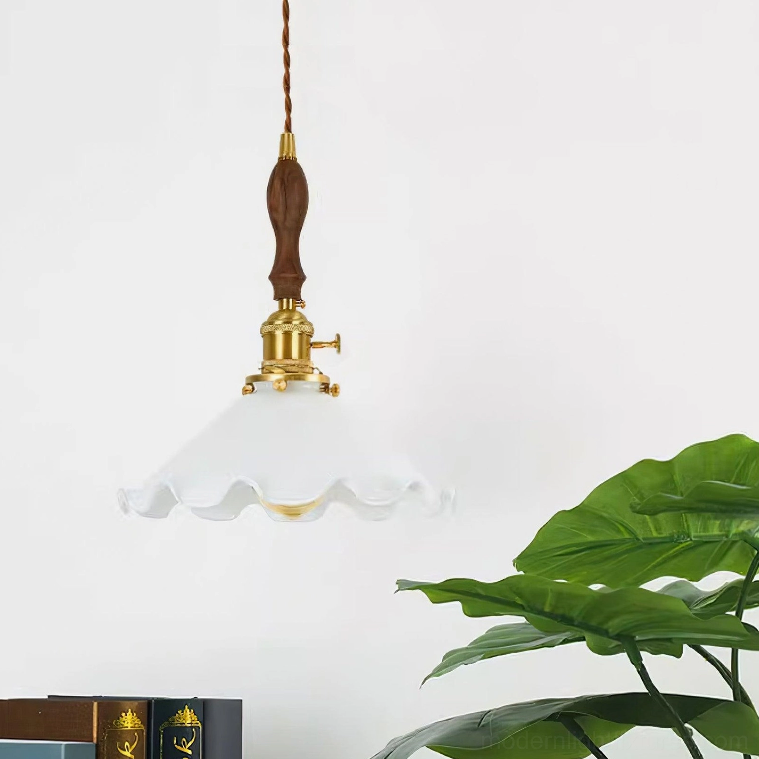 Gold-trimmed frosted glass flower pendant light with brass hardware in styled interior space