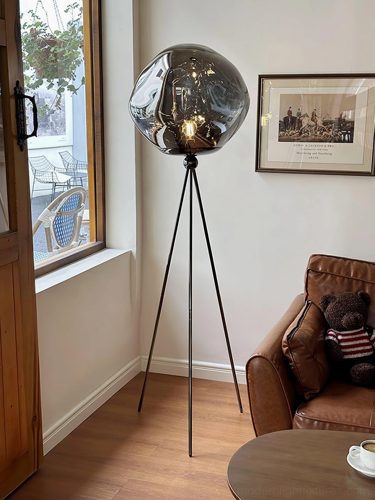 Contemporary tripod floor lamp in gold finish with molten lava glass creating beautiful light reflection
