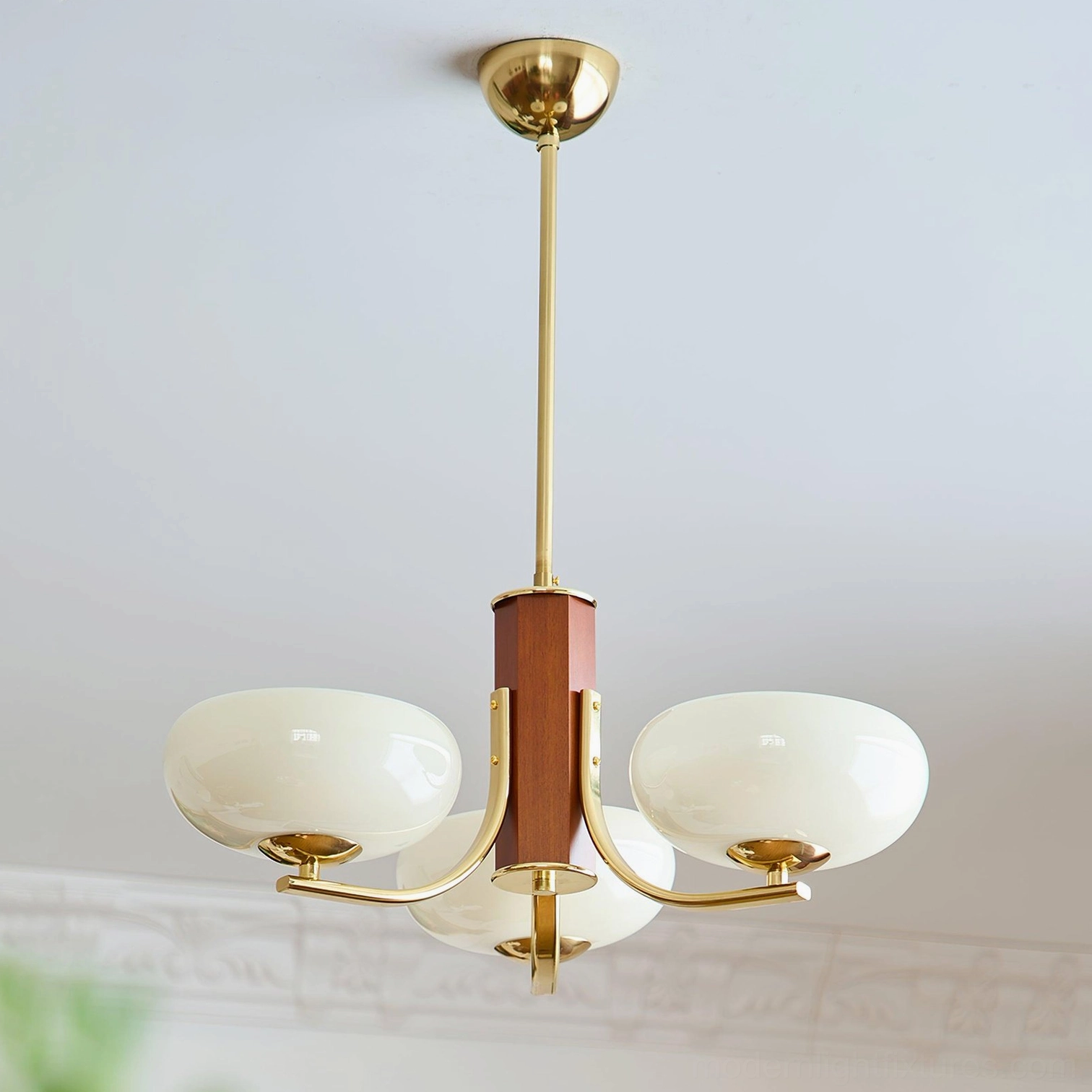 Gold and white Larenta Rico 3-head chandelier installation detail showing brass arms and white glass shades