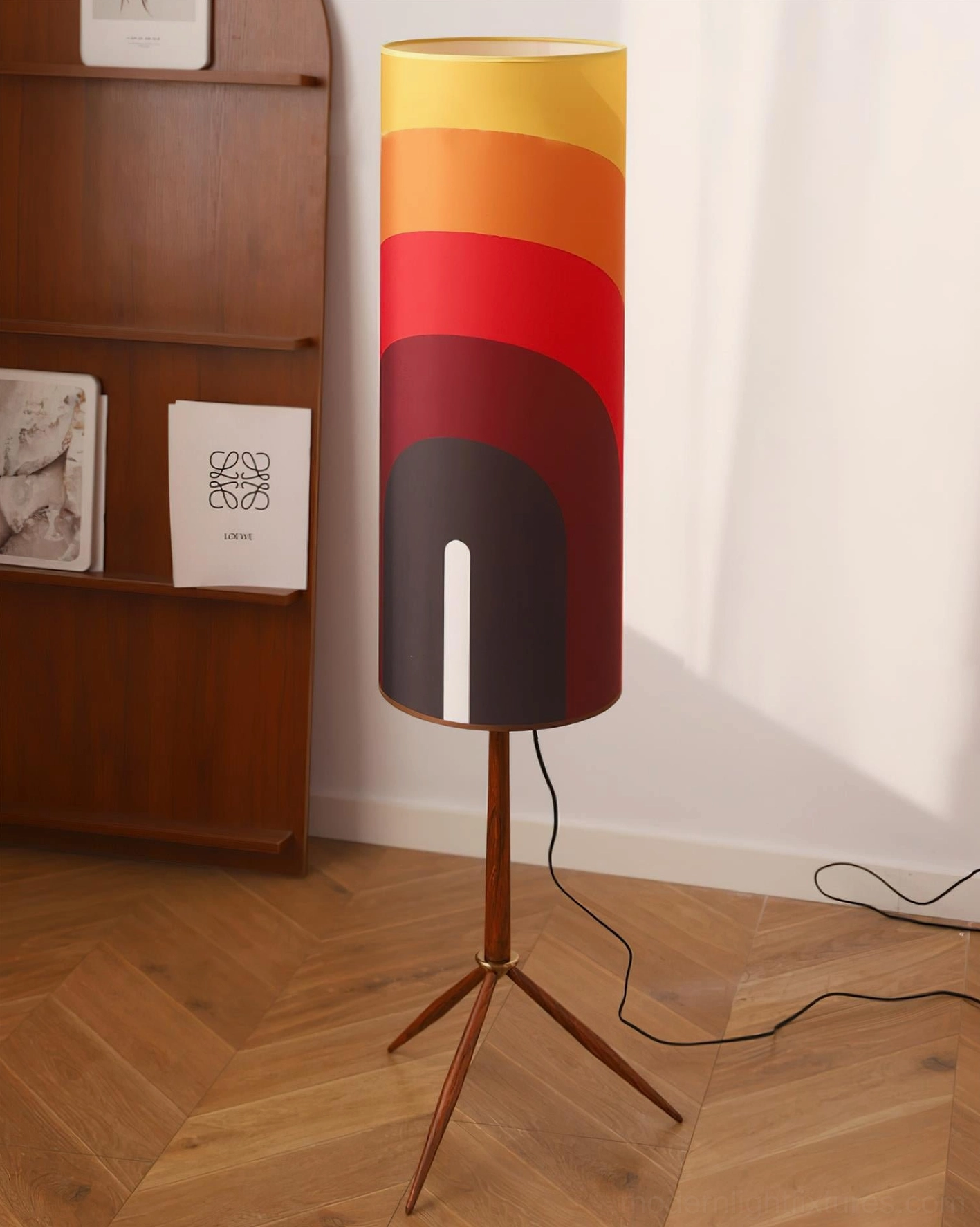 Warm gradient arc floor lamp standing beside wooden bookshelf on herringbone wood floor, showcasing interior design compatibility