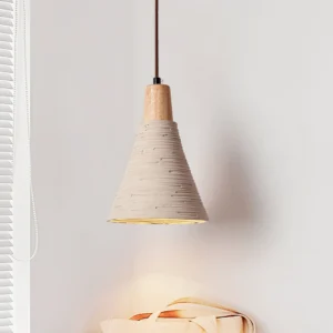 Grainline pendant light illuminated in indoor setting with window blinds, showing warm ambient glow from textured cement shade