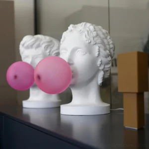 Pair of matching Greek bust table lamps with hot pink bubble shades displayed on dark home sideboard, decorative sculpture lighting