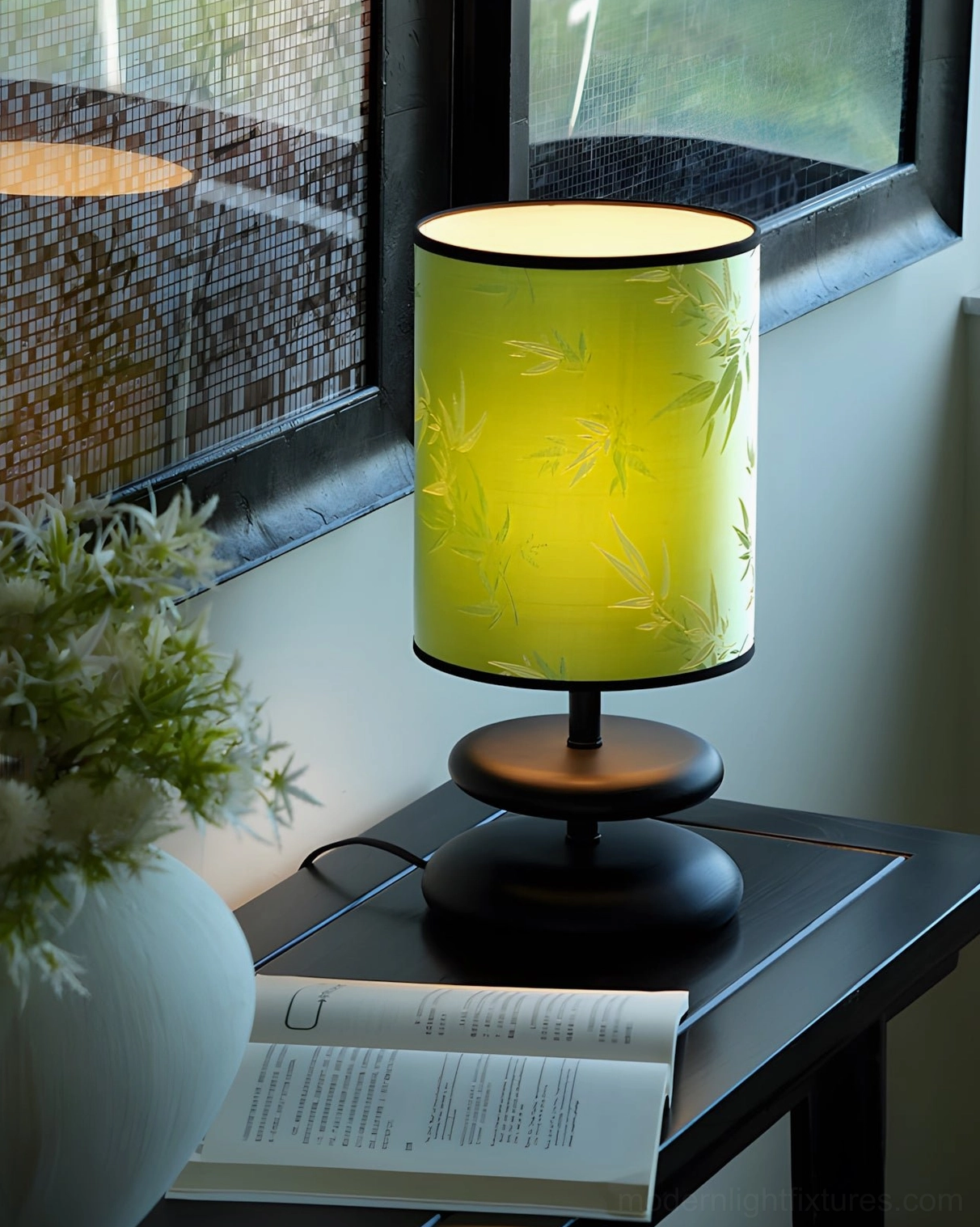 Green bamboo-print table lamp with dark wood and gold base, window side table with potted plant, three-quarter side view