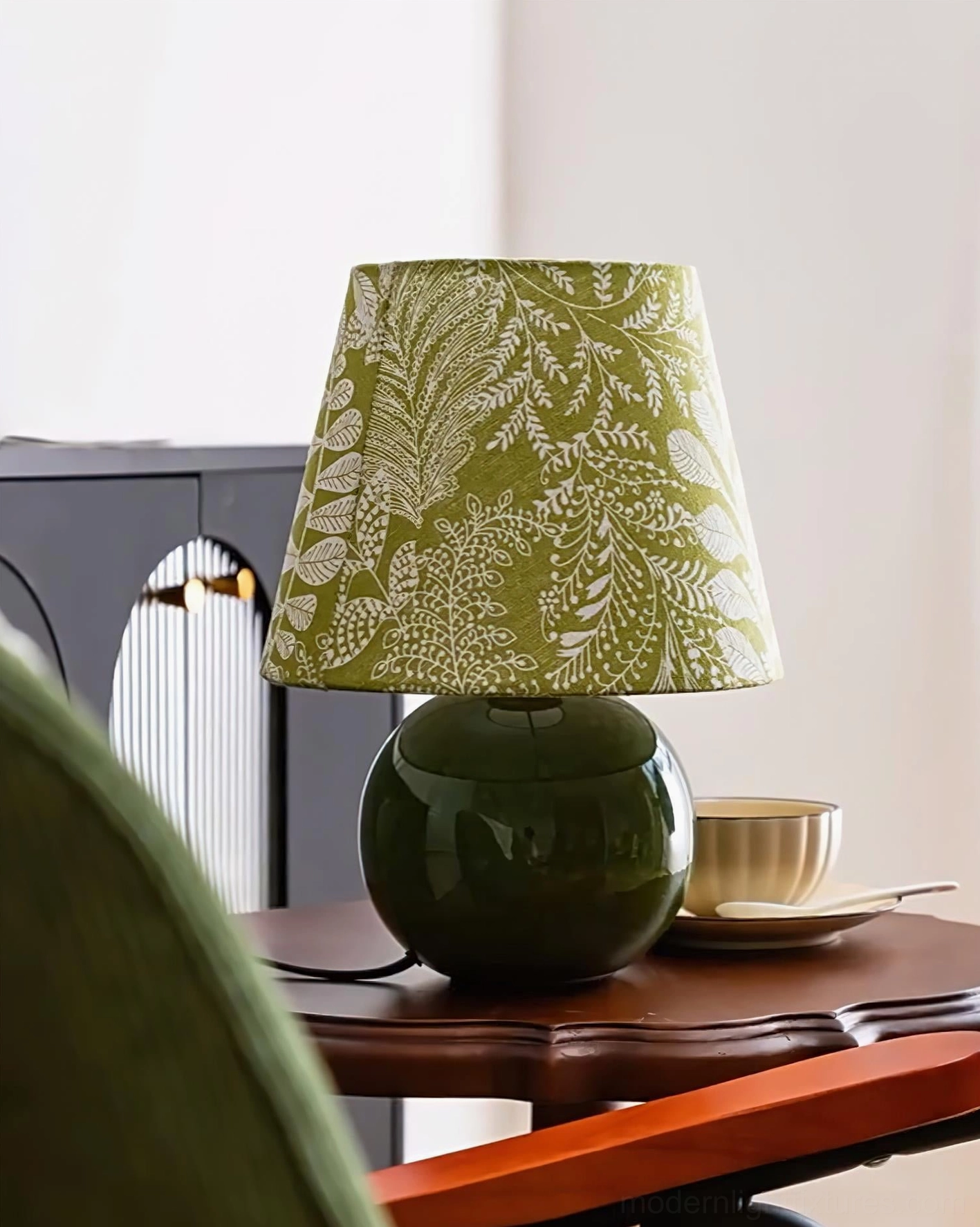 Green fabric shade table lamp positioned on wooden table with tableware