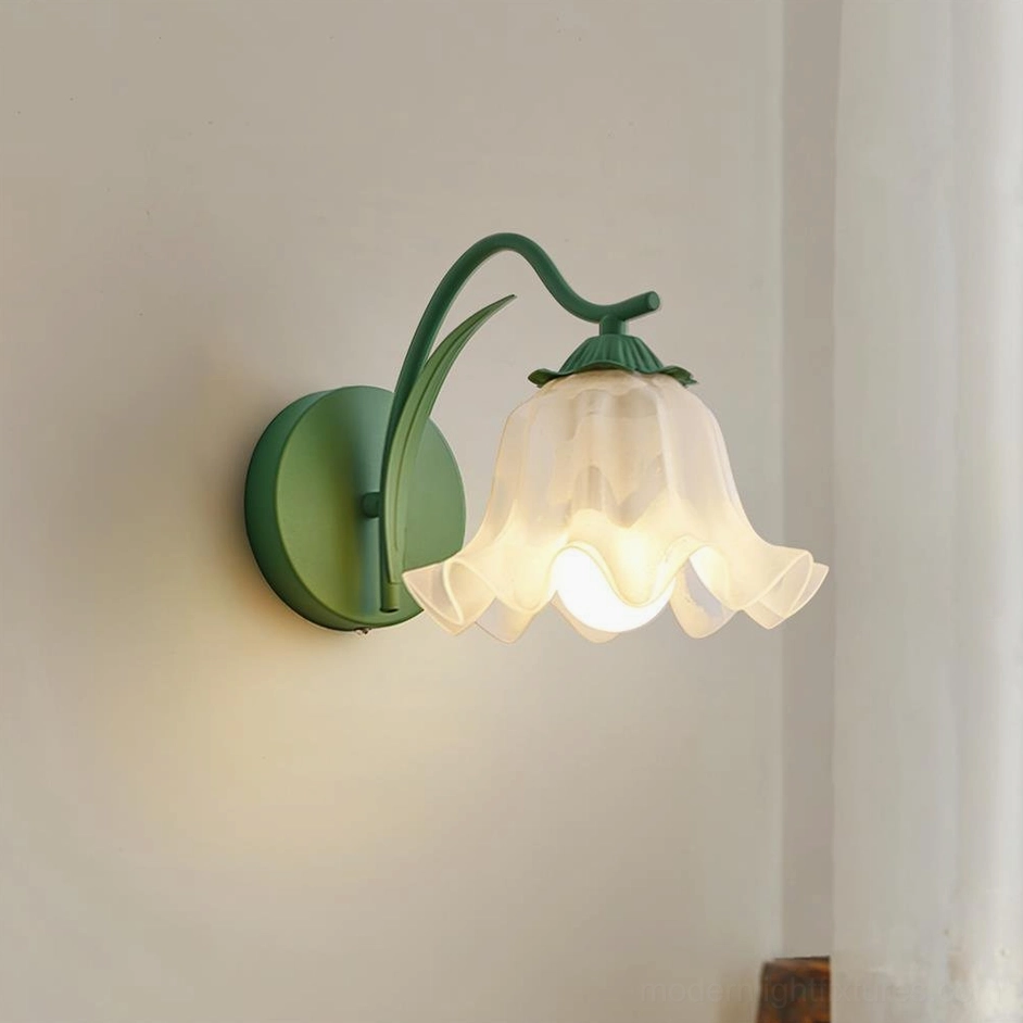 Green matte metal floral wall sconce with warm glowing frosted shade