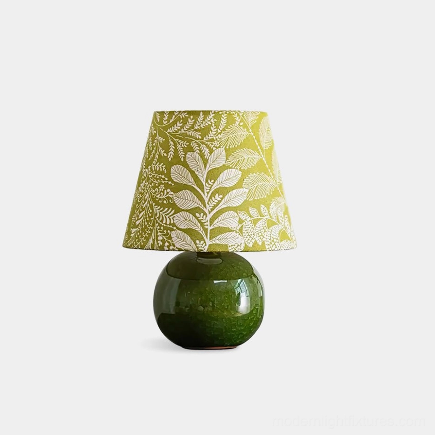 Green ceramic table lamp with botanical leaf print shade, front view on white background