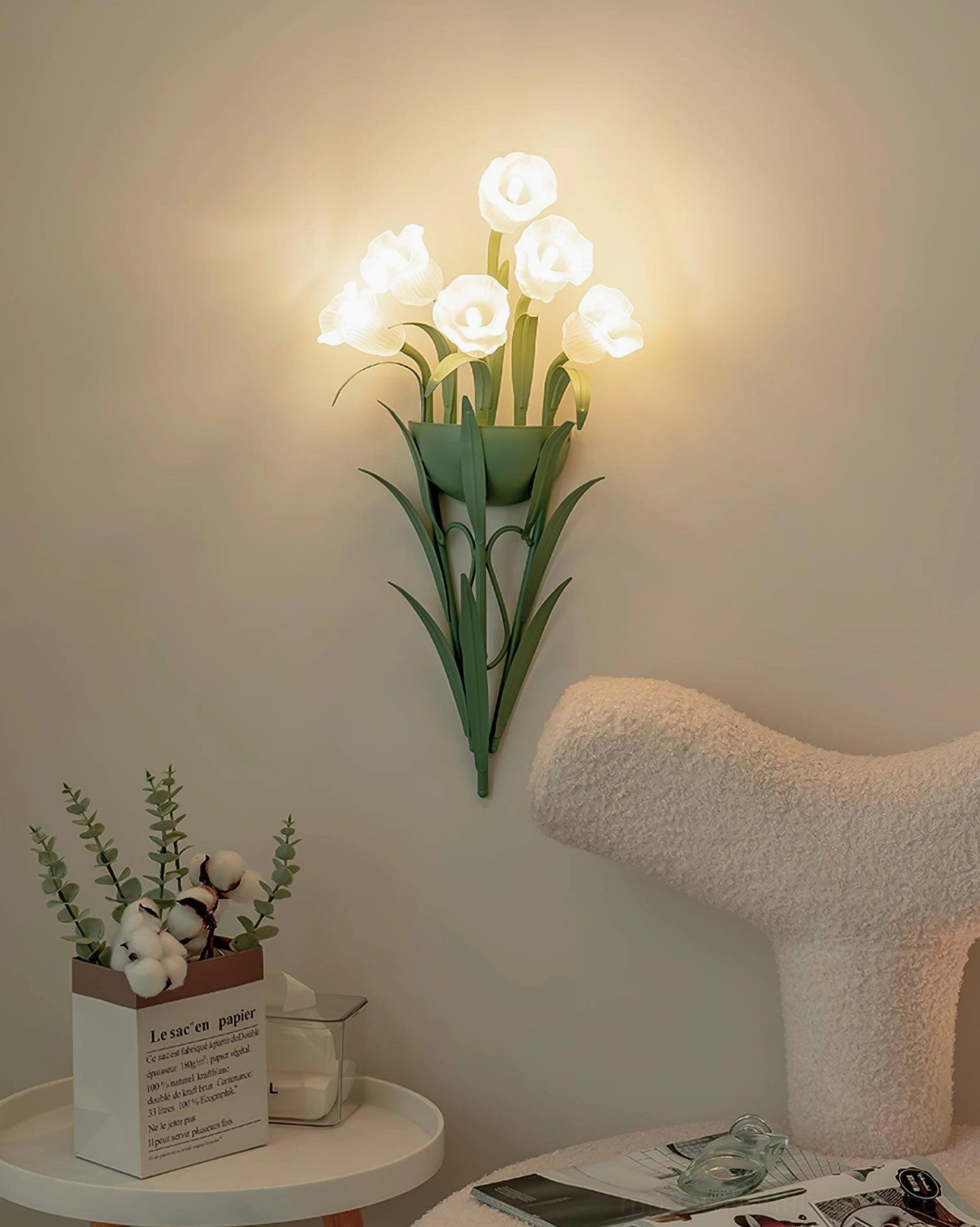 Green botanical wall sconce illuminated in bedroom corner with plush chair, floral wall lamp ambient lighting