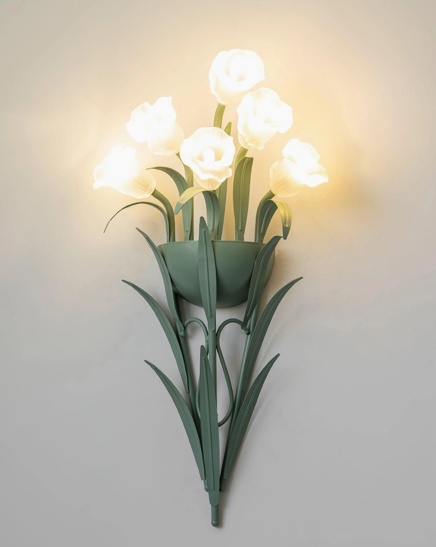 Green wall sconce with illuminated white flowers producing warm light, botanical wall lamp lit on white background