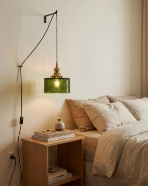 Vintage green glass pendant light hanging above bedside table in mid-century modern bedroom, creating warm amber glow